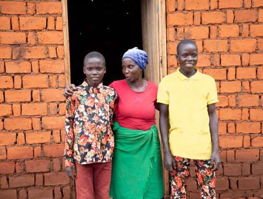 Aline Nibogora with sons Irumva (left) and Vyukesenge Aubi (right), standing outside their home.