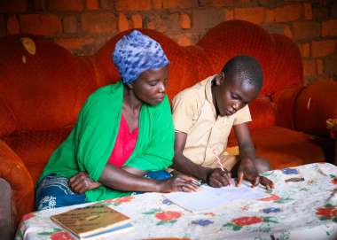 Aline Nibogora helping her son Vyukesenge Aubi with homework at their home in Makamba Province, Burundi.