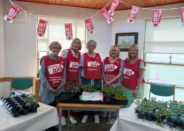 Women wearing Christian Aid tabards at a bake sale